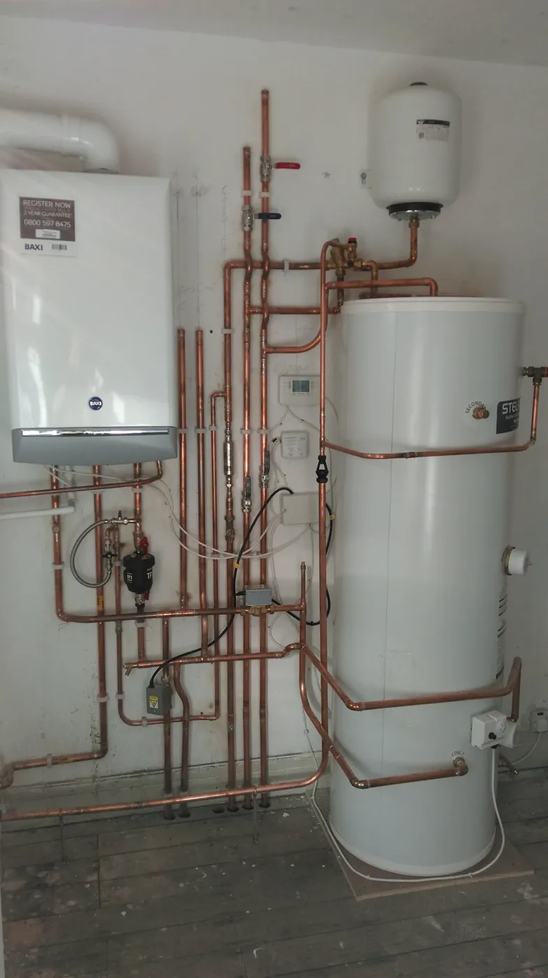 Wall-hung system boiler beside an unvented hot water cylinder with copper pipework